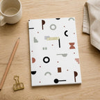 Shapes of Italy notebook on an oak desk with a pencil, brass clip and ceramic mug